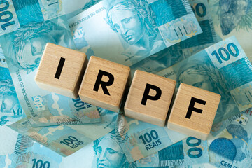 Fototapeta na wymiar IRPF, Imposto de Renda de Pessoa Física, English translation Personal Income Tax. Financial concept. Taxes in Brazil. written on wooden blocks, Brazilian money, calculator, business background