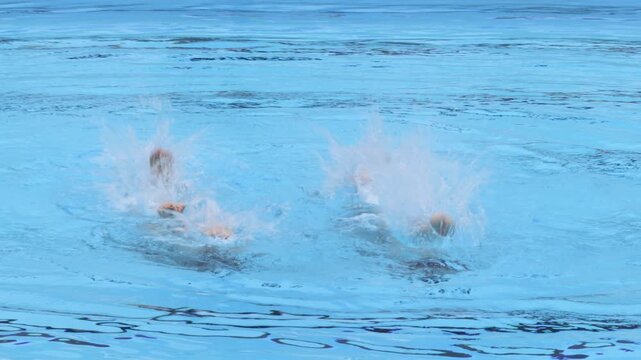 Team of artistic swimmers performing synchronized leg choreography during a routine in a swimming pool. Aquatic sport showcasing teamwork, precision, flexibility and elegance.