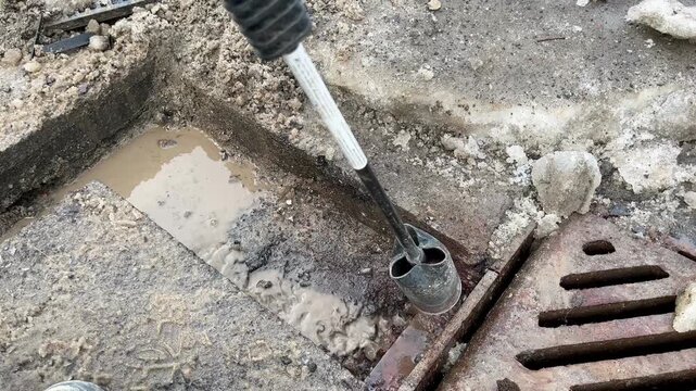  Worker melting ice with gas torch near drainage grate.