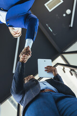 Business Partners Shaking Hands Over Tablet During Office Meeting, Diverse Professional Agreement