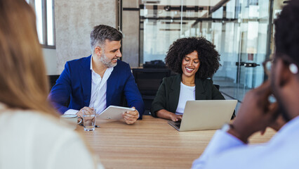 Diverse Colleagues Collaborating in a Modern Office Meeting Around Laptop and Tablet