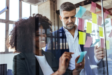 Business Colleagues Collaborating With Colorful Sticky Notes During Creative Office Brainstorming...