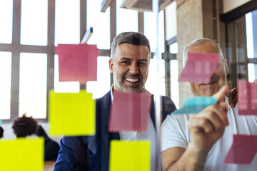 Smiling Colleagues Collaborating Over Colorful Sticky Notes During Creative Business Brainstorming...