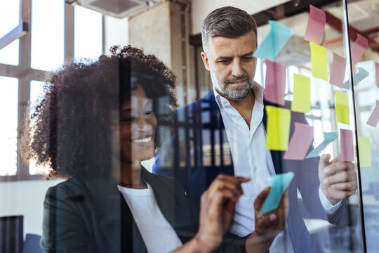 Business Colleagues Collaborating With Colorful Sticky Notes During Creative Office Brainstorming Meeting
