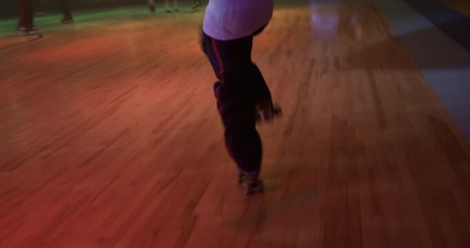 Epic steady cam shot following professional, young roller skater doing fun tricks on dance floor