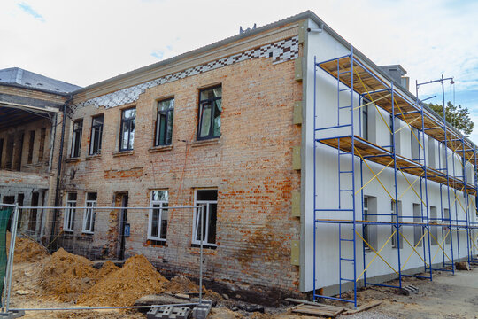 Renovation and repair of an old brick building with large blue metal scaffolding, restoring war damage and improving structure