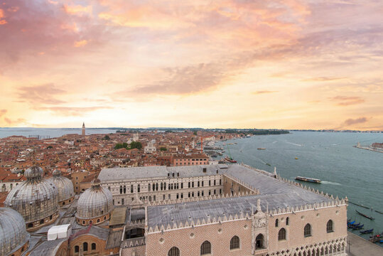 Ornate stone Doge Palace and domes of Venice basilica at pink sunset