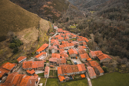 Stunning aerial drone perspective of Barcena Mayor, a historic mountain village in Cantabria. The image showcases the traditional stone houses.
