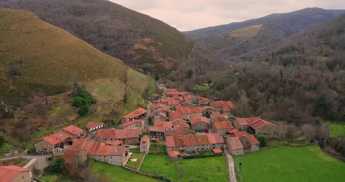 Slow cinematic aerial shot approaching Barcena Mayor, one of the oldest and most beautiful villages in Spain. The footage captures the rustic stone buildings.