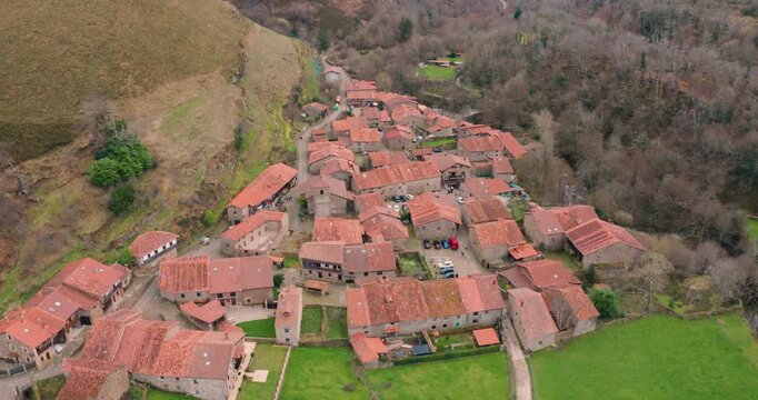 Slow cinematic aerial shot approaching Barcena Mayor, one of the oldest and most beautiful villages in Spain. The footage captures the rustic stone buildings.
