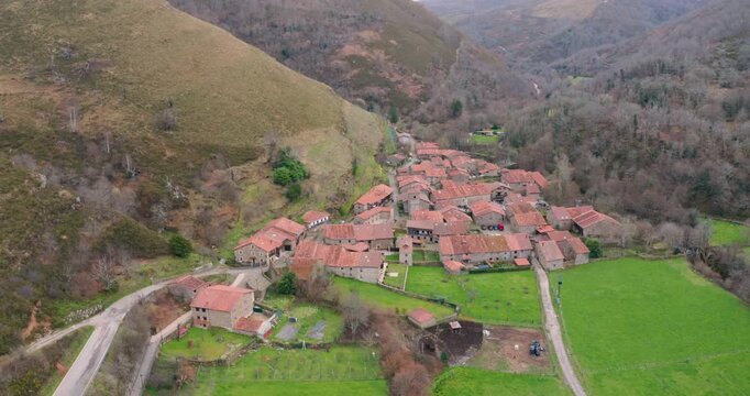 Slow cinematic aerial shot approaching Barcena Mayor, one of the oldest and most beautiful villages in Spain. The footage captures the rustic stone buildings.