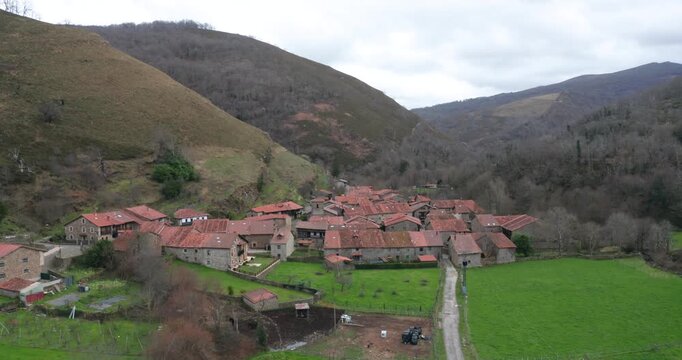 Slow cinematic aerial shot approaching Barcena Mayor, one of the oldest and most beautiful villages in Spain. The footage captures the rustic stone buildings.