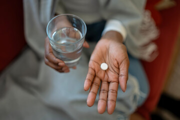 Person holding pill and glass of water