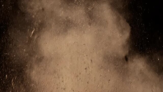 Brown earth explosion erupting with flying rocks on black background