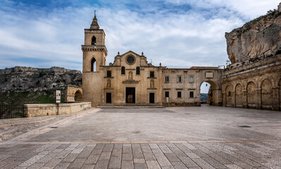 Fototapeta premium San Pietro Caveoso church in Matera placed on the precipice of the canyon carved by the Gravina River and on its right the arch that introduces in Sasso Caveoso