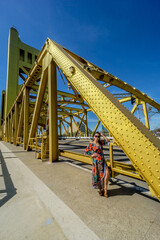 Fototapeta premium A woman stands in front of a yellow bridge, posing for a picture