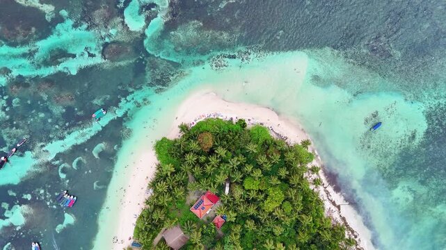 Top down aerial drone footage showing coral reef patterns and bright turquoise Caribbean water around Cayo Zapatilla island in Panama.