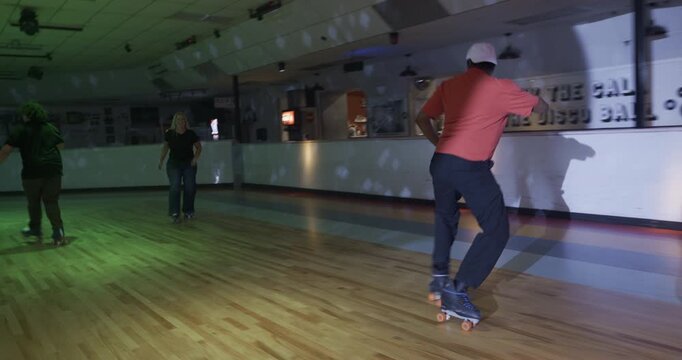 Cinematic steady cam following young professional skater doing smooth moves across disco floor near group