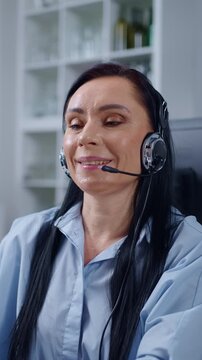 Focused customer support agent wearing headset working at computer in modern office environment, providing professional online assistance and remote communication service