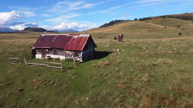 Aerial drone footage flying over the Marcesina plateau in Italy, showcasing the iconic "Casoni" mountain huts. The video captures the peaceful, isolated nature of these ancient rustic cabins