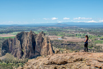A woman stands on a rocky hill overlooking a beautiful landscape