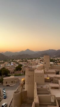 Historic Bahla Fort built with traditional mud architecture standing on rocky ground under clear blue sky showing ancient Omani heritage. Bahla, Oman - February 17 2026