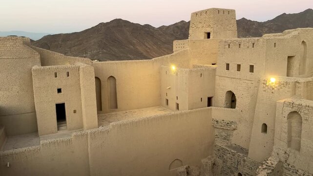 Historic Bahla Fort built with traditional mud architecture standing on rocky ground under clear blue sky showing ancient Omani heritage. Bahla, Oman - February 17 2026