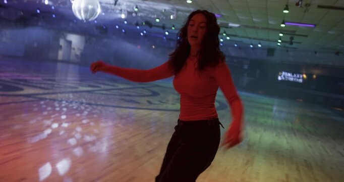 Beautiful young woman doing amazing, stylized tricks on empty, hazy disco floor - steady cam movement