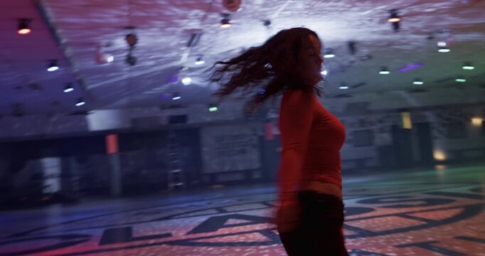 Cinematic silhouette steady cam movement with talented young skater alone on disco floor