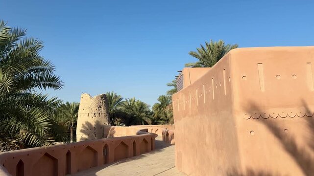 Historic Al Aqr Wall in Nizwa showing traditional Omani architecture with mud buildings palm trees and old defensive structure in a famous cultural landmark. Nizwa, Oman - February 20, 2026