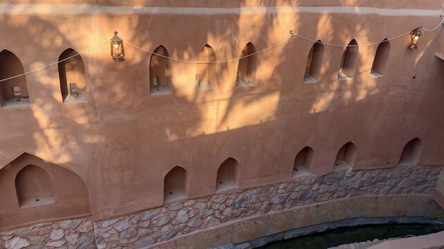 Historic Al Aqr Wall in Nizwa showing traditional Omani architecture with mud buildings palm trees and old defensive structure in a famous cultural landmark. Nizwa, Oman - February 20, 2026