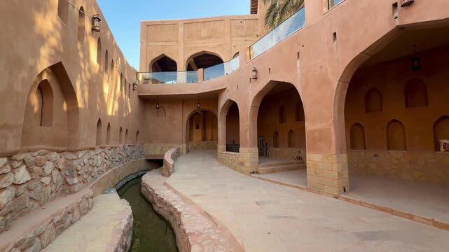 Historic Al Aqr Wall in Nizwa showing traditional Omani architecture with mud buildings palm trees and old defensive structure in a famous cultural landmark. Nizwa, Oman - February 20, 2026