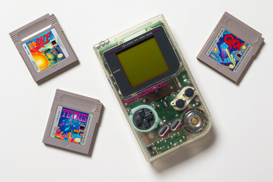 Nintendo Game Boy DMG Play It Loud. The handheld console is transparent and on a white background. There are game cartridges around it.