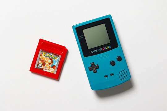 Nintendo Game Boy Color. The handheld console is teal and on a white background. There is a Pokemon Red cartridge.