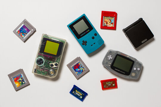 Different Nintendo Game Boy console models with multiple games. Transparent DMG Play It Loud, Teal Color, Glacier Blue Advance and Onix Black Advance SP. The consoles are on a white background.