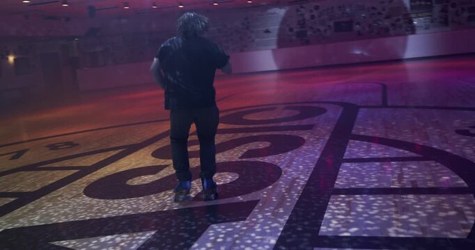 Cinematic silhouette of professional skater doing awesome spins and moves under disco ball - wide, steady cam movement