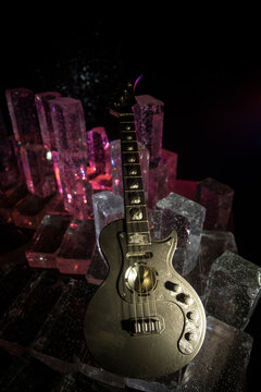 Music Concept: Guitar Miniature on a Dark Background with Vivid Light, Smoke, and Fire Effects. Golden electro guitar under a Dramatic Spotlight.