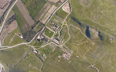 Aerial drone view of Tripolis Antik Kenti near Buldan in Denizli, Turkey, showcasing ancient Roman ruins, stone structures, columns, and scenic hillside landscape from above.