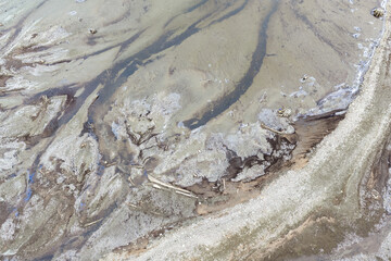 Obraz premium Aerial View of Muddy Shoreline and Driftwood on Exposed Riverbed at Low Tide, BC, Canada