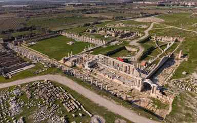 Aerial drone view of Tripolis Antik Kenti near Buldan in Denizli, Turkey, showcasing ancient Roman ruins, stone structures, columns, and scenic hillside landscape from above.