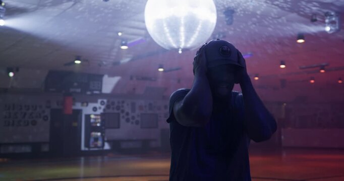 Silhouette of young skater doing awesome moves on disco dance floor - steady cam shot