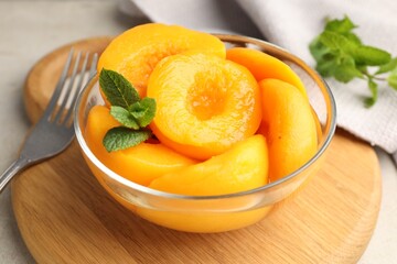 Pickled peaches and mint leaves in bowl on light grey table, closeup © New Africa