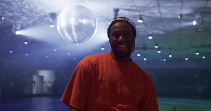 Male skater posing in front of sparkling disco ball - medium steady cam shot