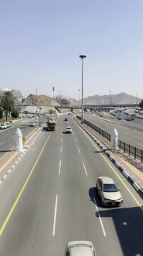 Bustling highway view in Makkah featuring the historic white Haram boundary pillars near Masjid Aisha Taneem. A key location for pilgrims entering the sacred city for Umrah and Hajj.