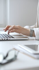 Professional businesswoman working intently on laptop, wearing tailored beige suit and silver...
