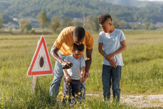 Family members notice a tick warning sign while hiking and apply repellent to protect their child from ticks and diseases.