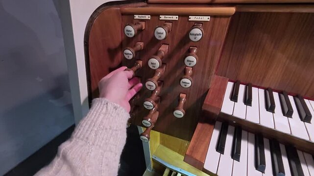 POV of an organist's hand pulling and pushing some organ stops