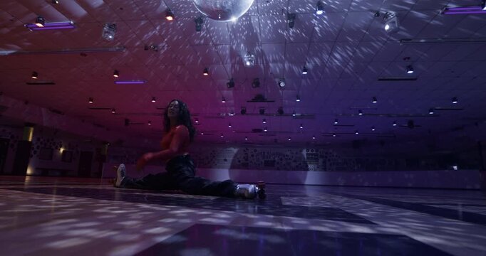 Epic splits move on disco dance floor by professional female skater - low, wide shot