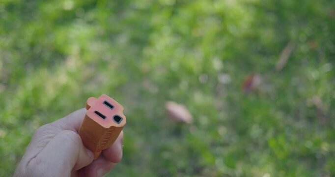 Hand holding orange extension cord over green grass