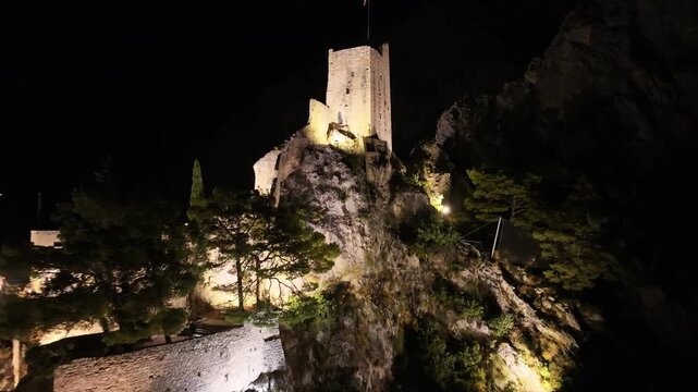 Mirabela tower glowing above Omis historic center during night.